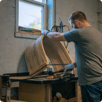 Worker shaping curved wood using workshop machinery