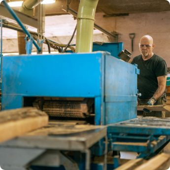Worker operating lumber processing machinery in a sawmill