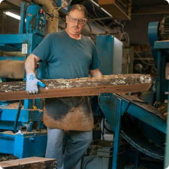 Worker handling a log at a sawmill processing machine