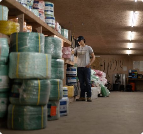 Employee standing in a marine supply warehouse surrounded by coils of rope and fishing gear