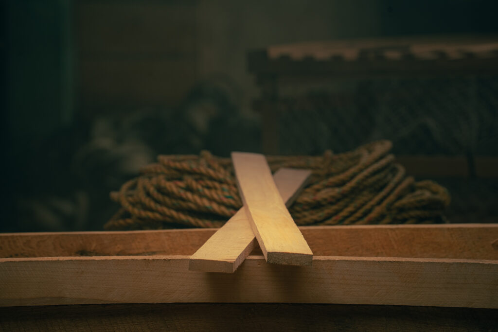 Wooden trap runners placed on lobster trap frame with rope in background
