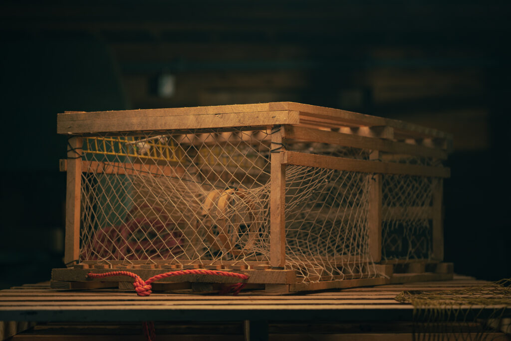 Traditional square wooden lobster trap with netting and reinforced frame